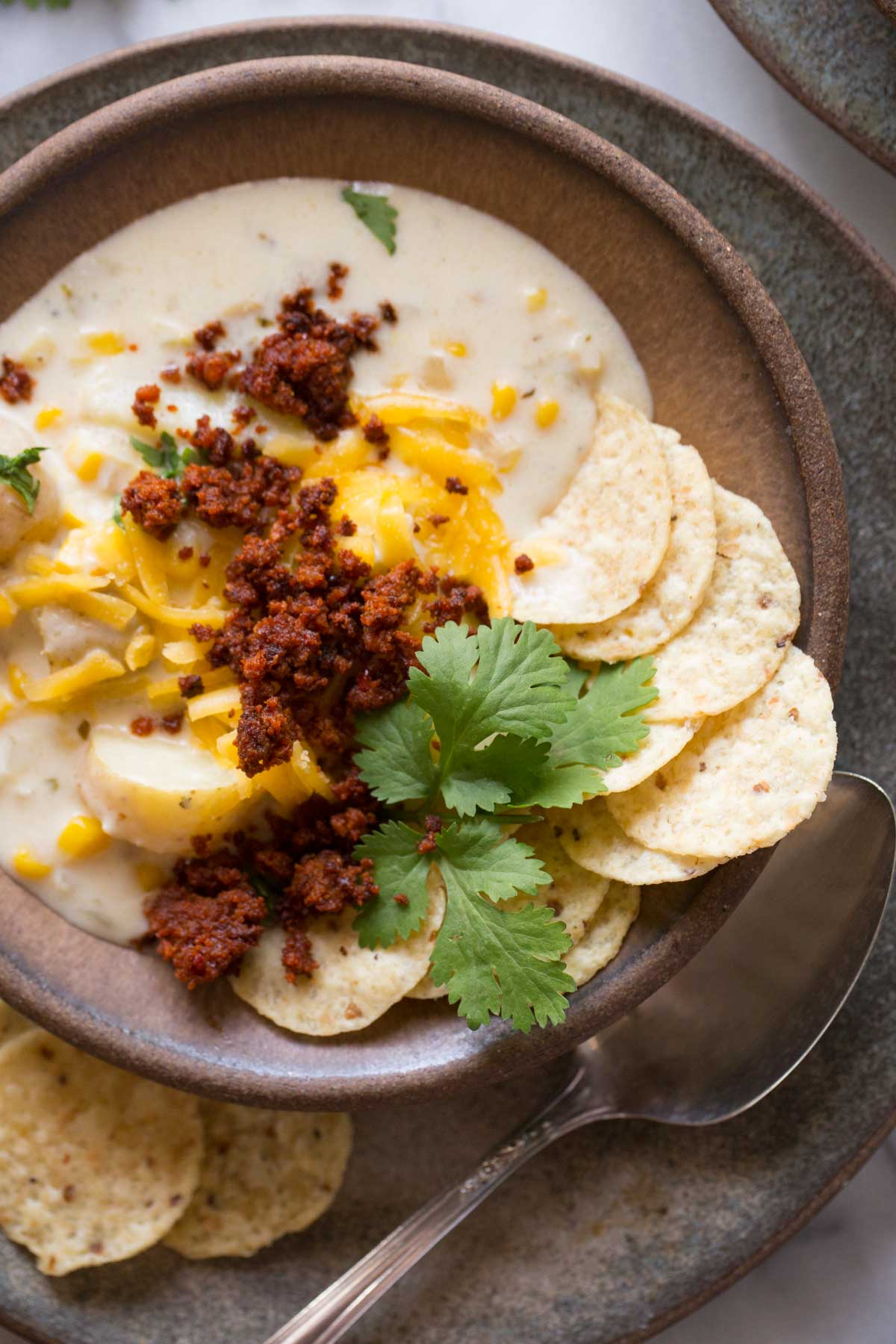 Overhead view of Creamy Corn Chowder With Chorizo in a brown bowl. 