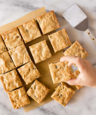 Overhead view of blondies with a child's hand taking one.