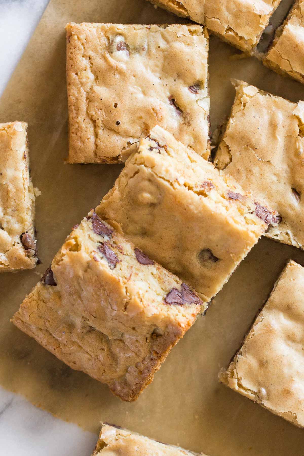 Close up overhead view of cut up blondies on parchment paper. 