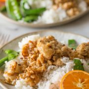 Two plates of Easy Orange Chicken with white rice and snow peas.