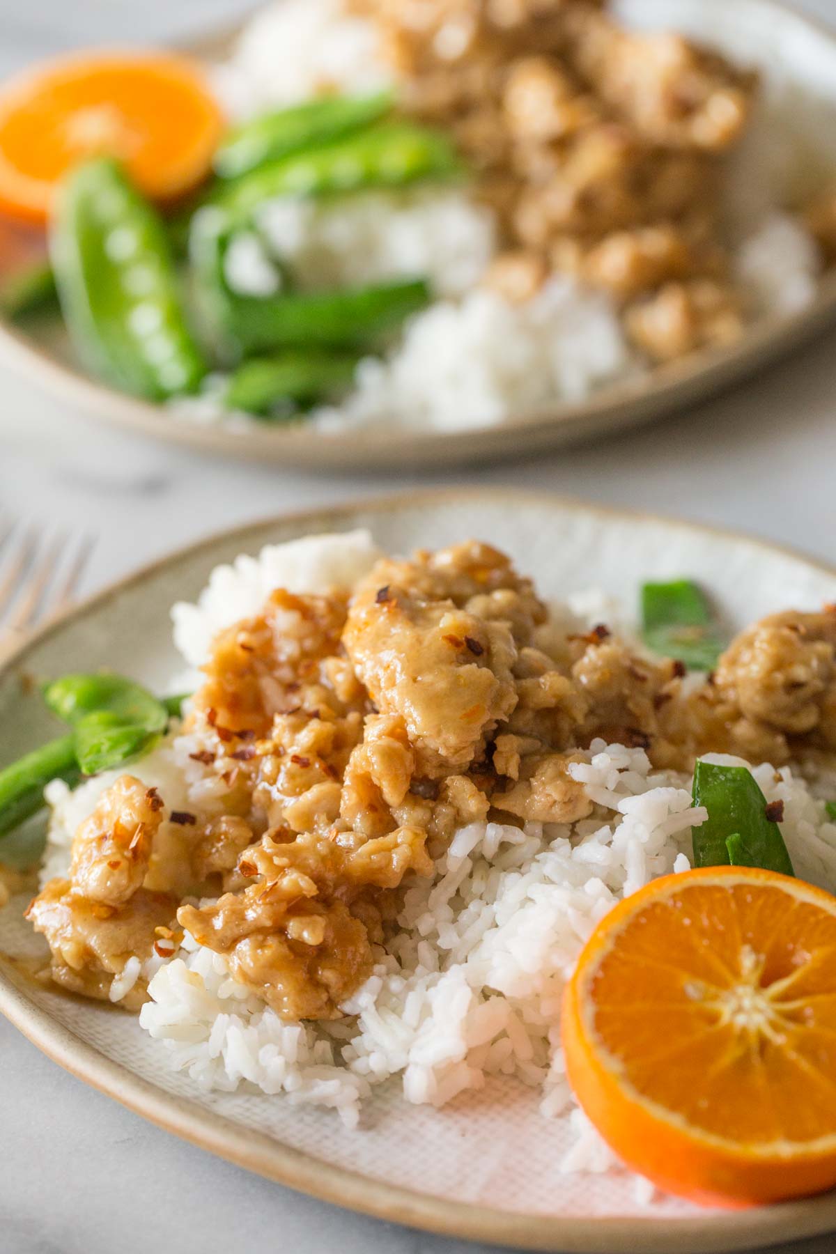 Two plates of Easy Orange Chicken on a white background. 