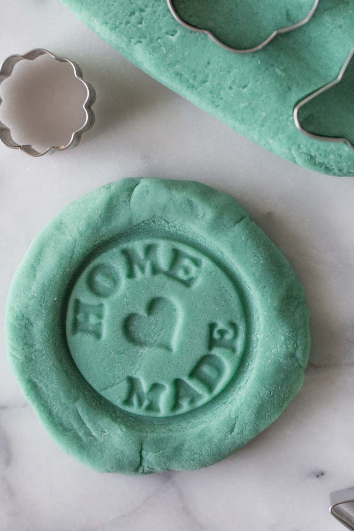 A close-up view of blue playdough with a homemade stamp pressed into the dough. 