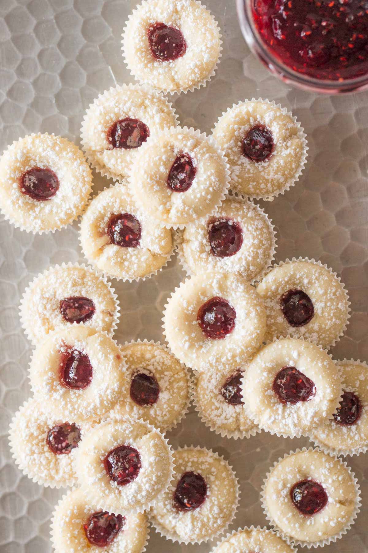 Overhead view of Mini Raspberry Almond Tarts with powdered sugar on a silver tray.  