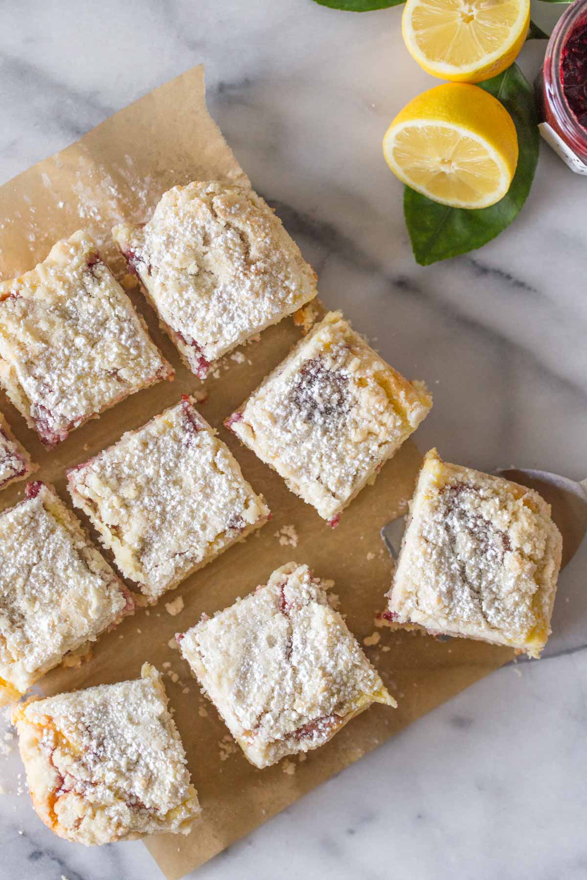 Overhead shot of cut pieces of Lemon Raspberry Cream Cheese Coffee Cake on a piece of parchment paper on a marble slab. 