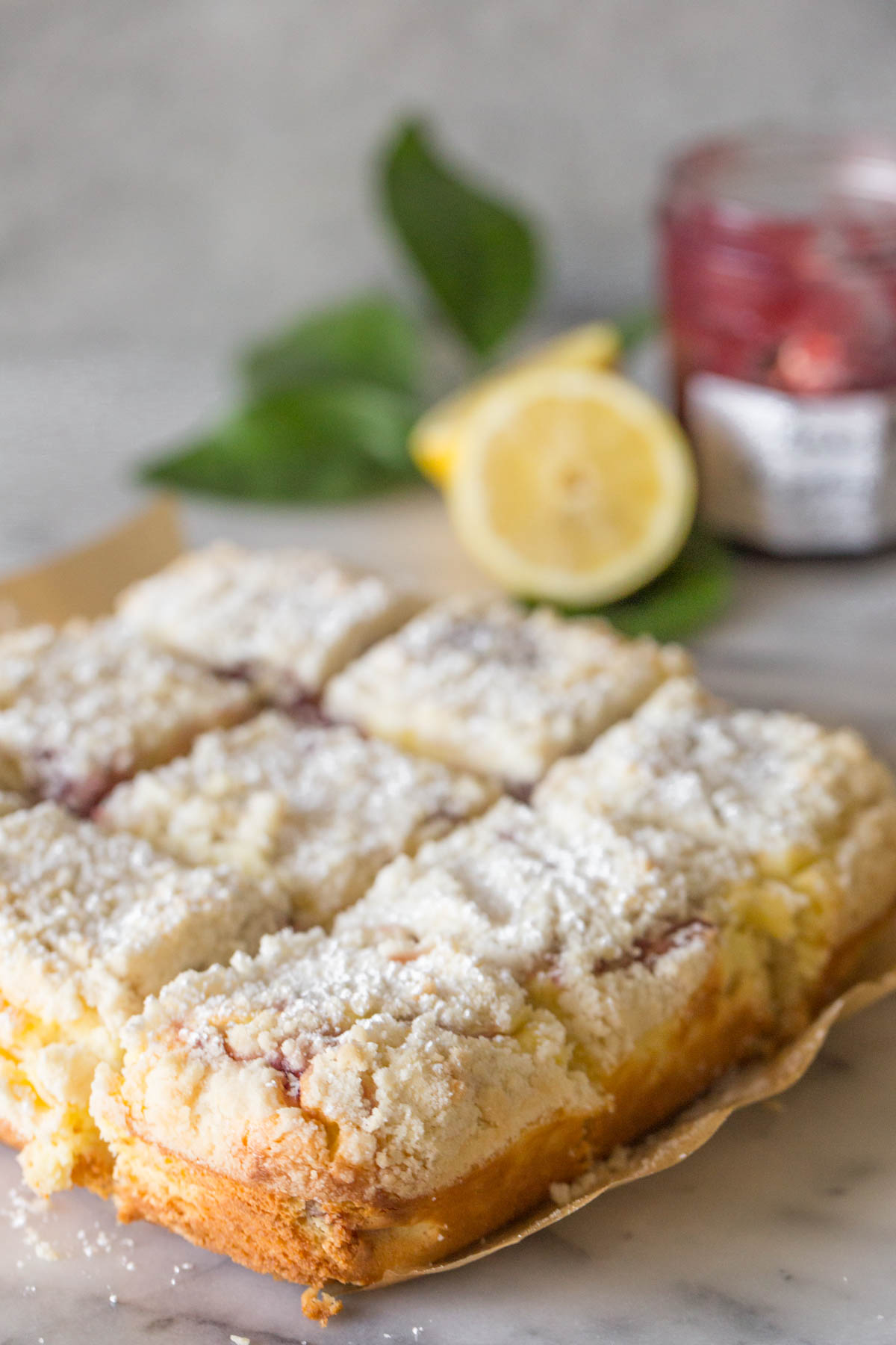Lemon Raspberry Cream Cheese Coffee Cake dusted in powdered sugar with a grey background. 