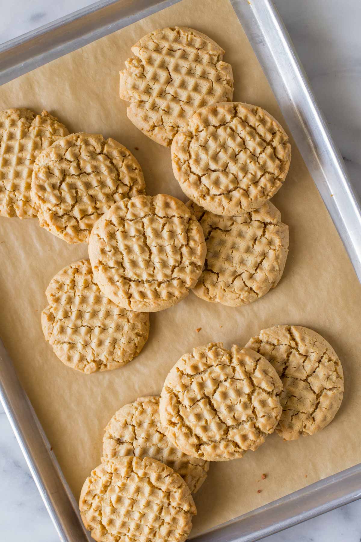 Overhead view of Soft and Chewy Peanut Butter Cookies on a parchment lined baking sheet. 