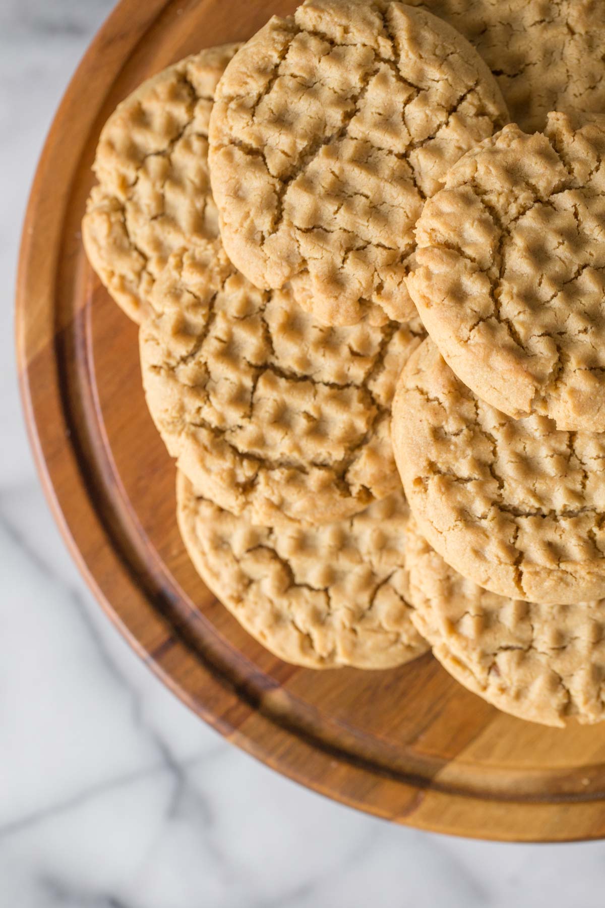 Overhead view of the tops of Soft and Chewy Peanut Butter Cookies on a wooden cake stand. 