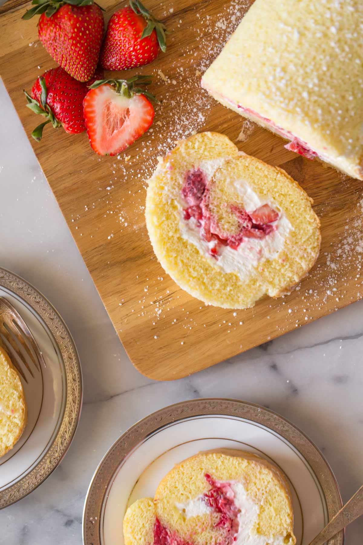  Draufsicht auf Vanillekuchenrolle auf Holzschneidebrett. 