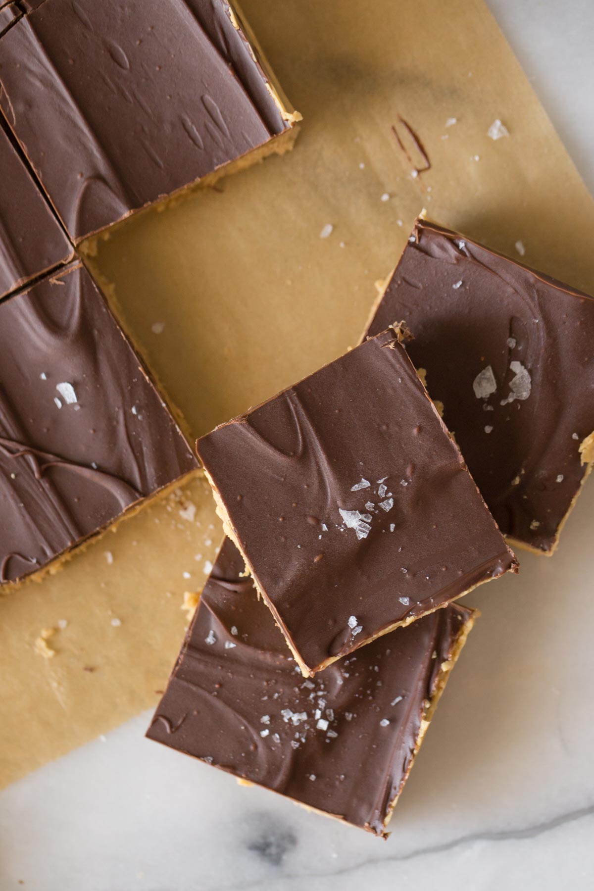 Overhead view of Chocolate Peanut Butter Bars stacked on parchment paper. 