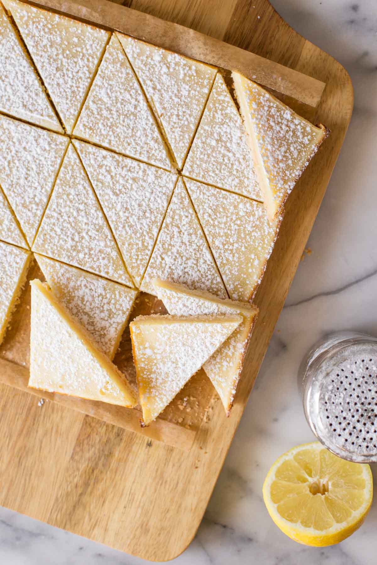 Overhead shot of cut Swedish Lemon Bars on a wooden cutting board. 