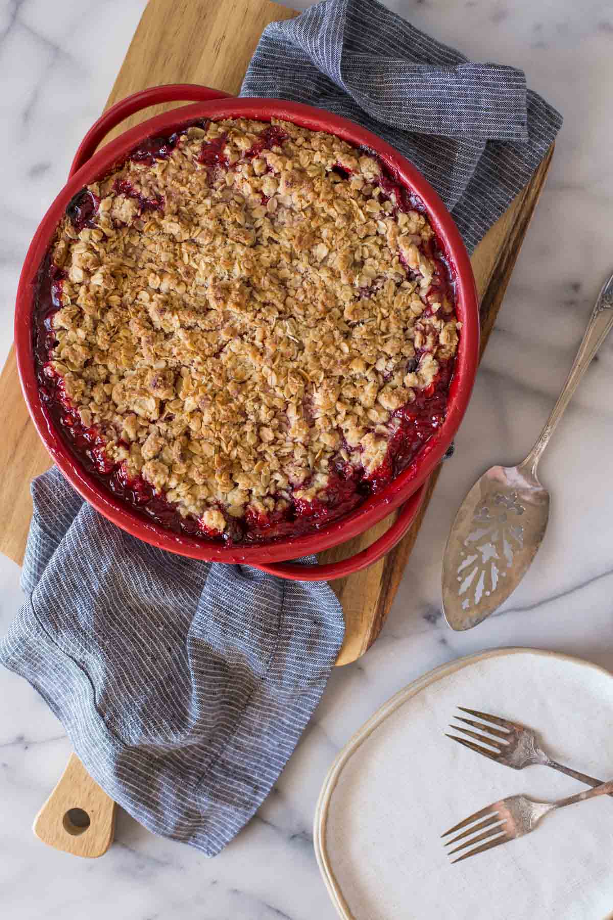 Overhead shot of a whole Berry Crumble Pie on a wooden cutting board.  