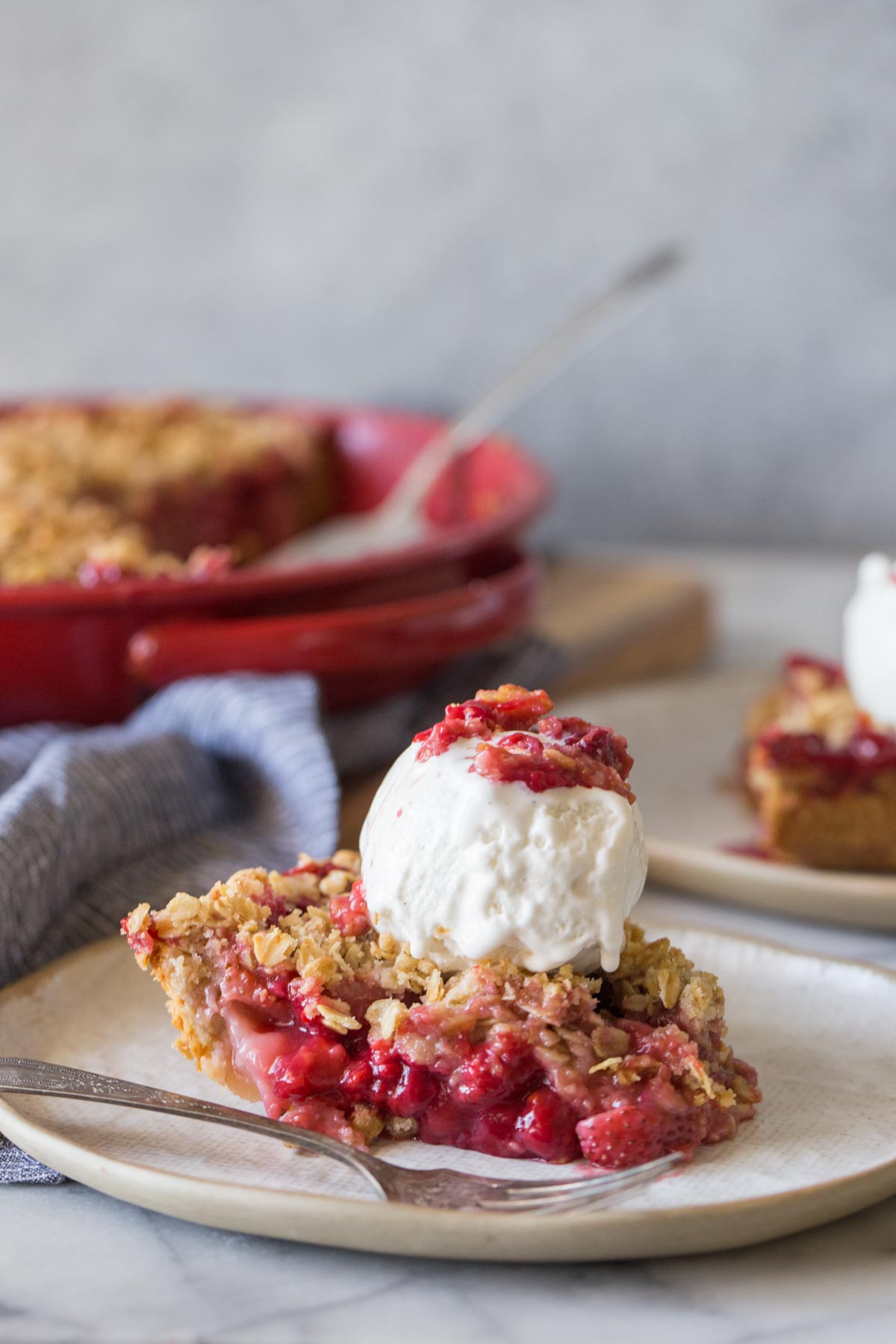 A slice of Berry Crumble Pie topped with a scoop of vanilla ice cream.  