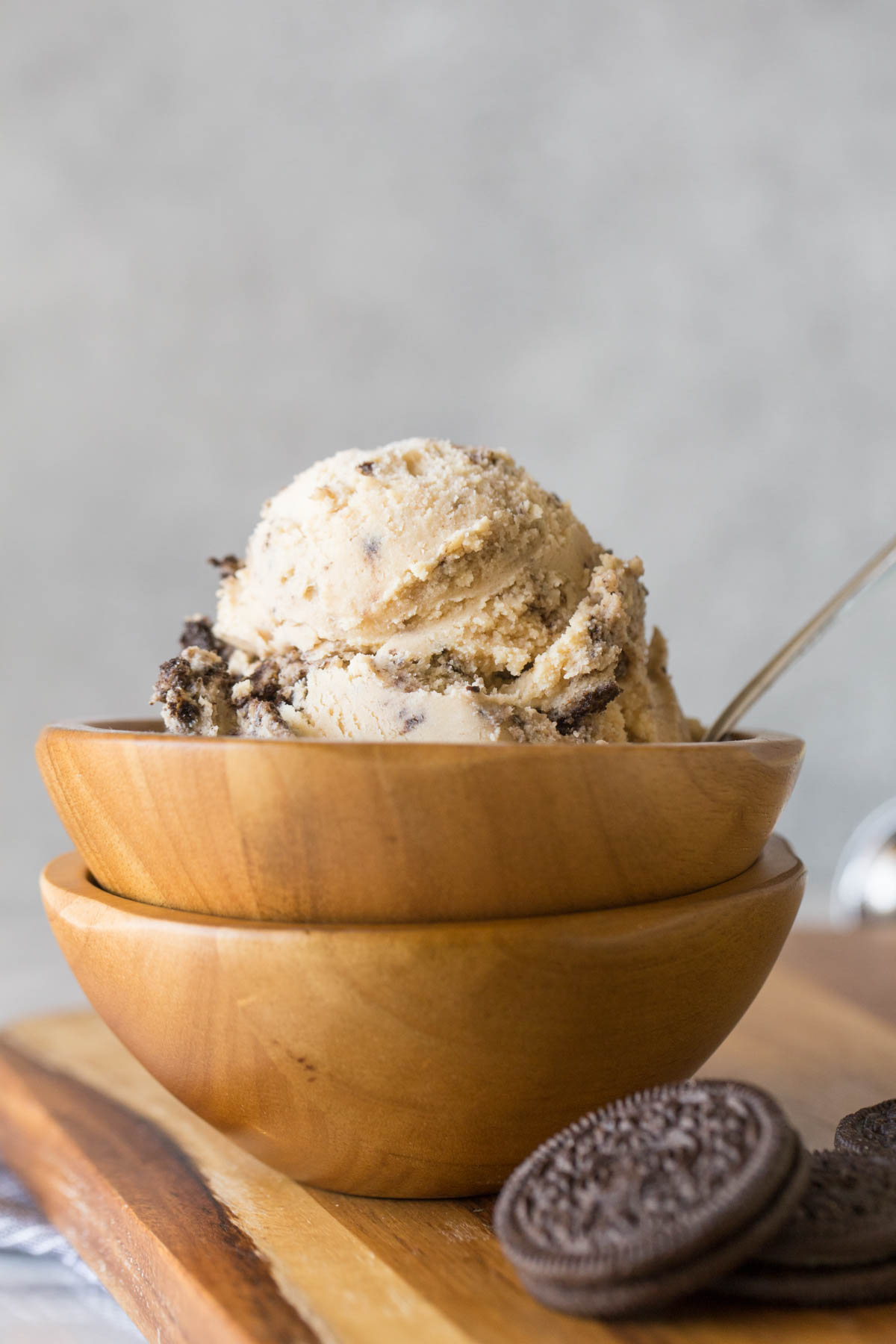 Peanut Butter Oreo Ice Cream in a wood bowl that is stacked on another wood bowl, with a few Oreo Cookies next to it.  