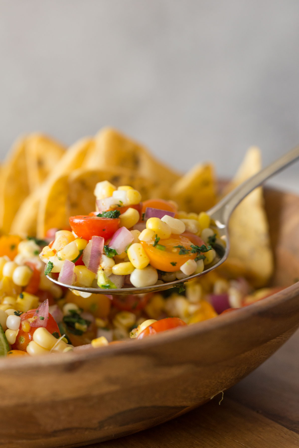 Close up shot of a spoon full of Honey Lime Corn Salsa over the serving bowl.