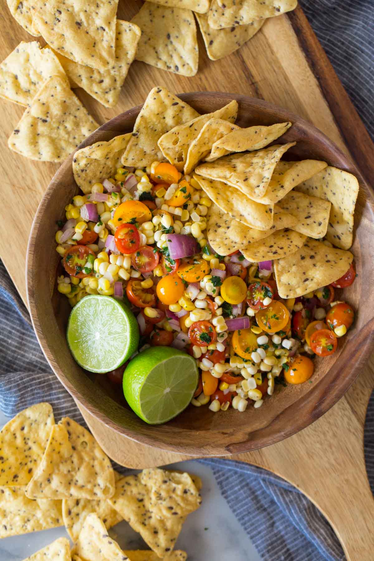 Overhead shot of Honey Lime Corn Salsa in a wood serving bowl with a sliced lime and tortilla chips.  