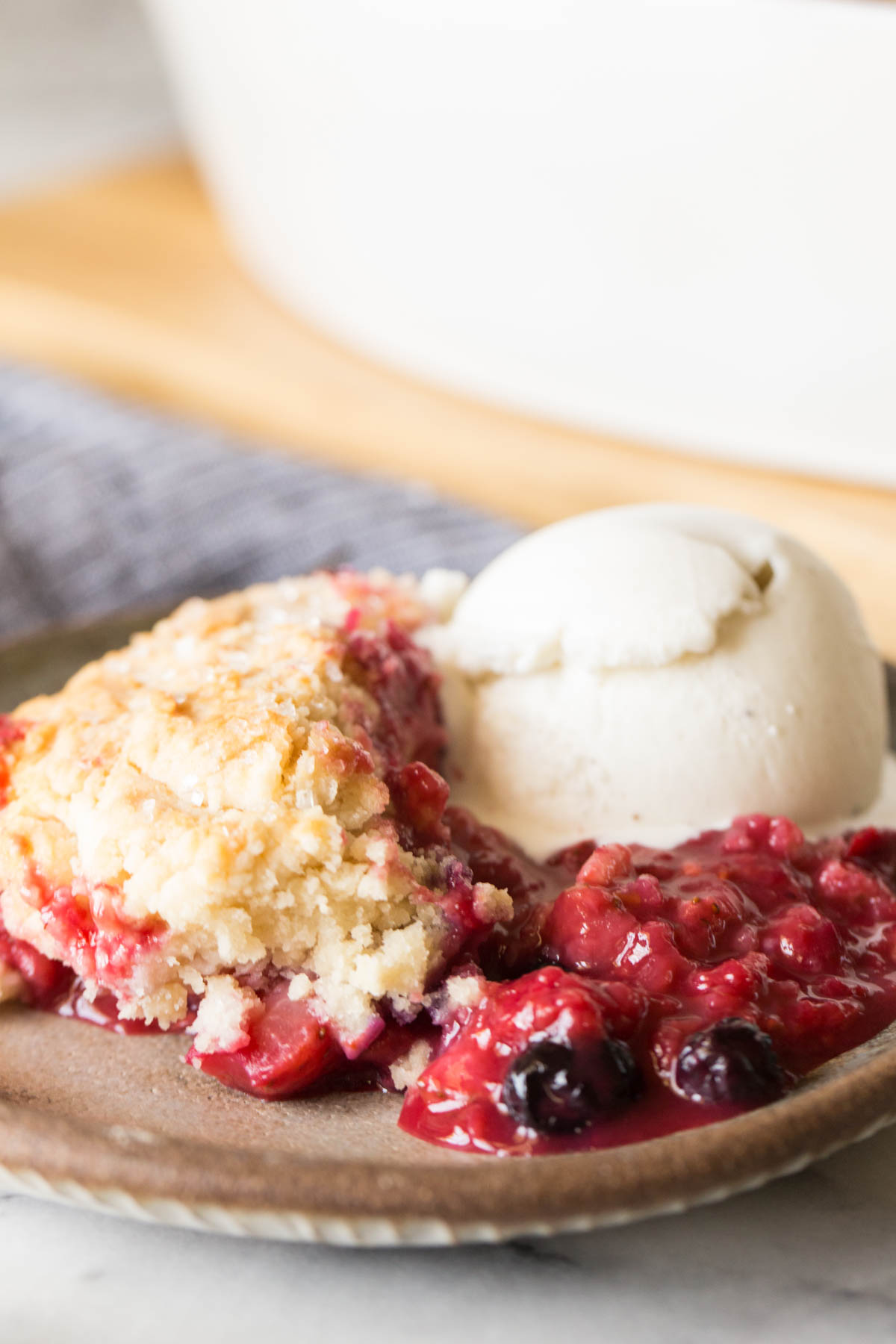 Close up shot of Triple Berry Cobbler on a plate with a scoop of vanilla ice cream.  