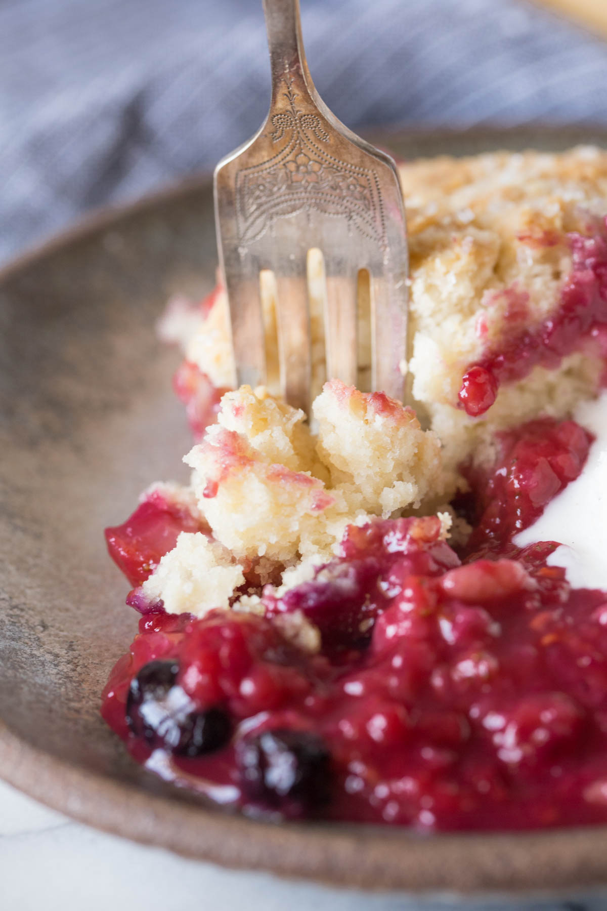 Close up shot of a fork in the Triple Berry Cobbler on a plate.  
