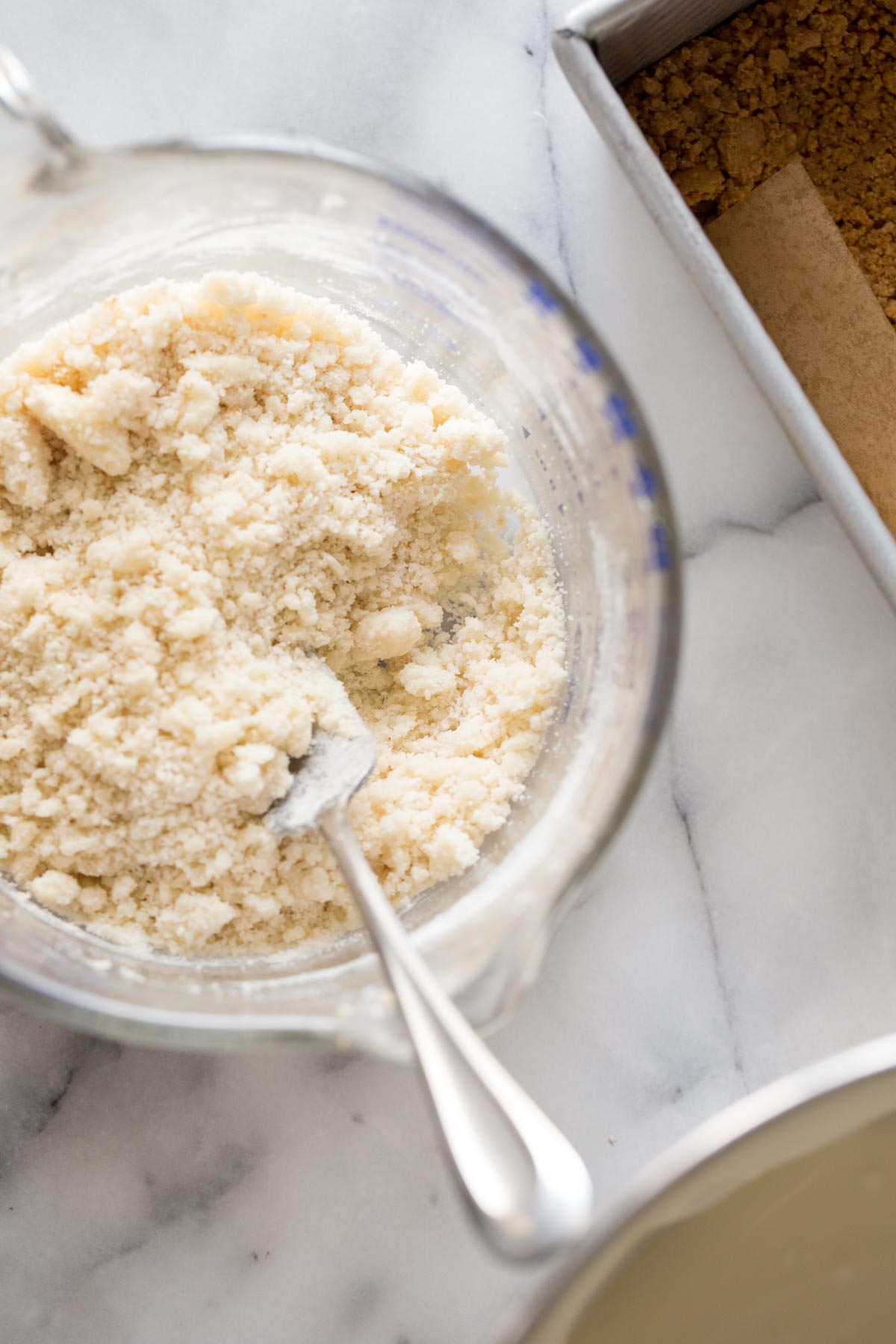 Overhead shot of the the streusel topping in a glass measuring bowl for the Cheesecake Bars With Berry Streusel.  