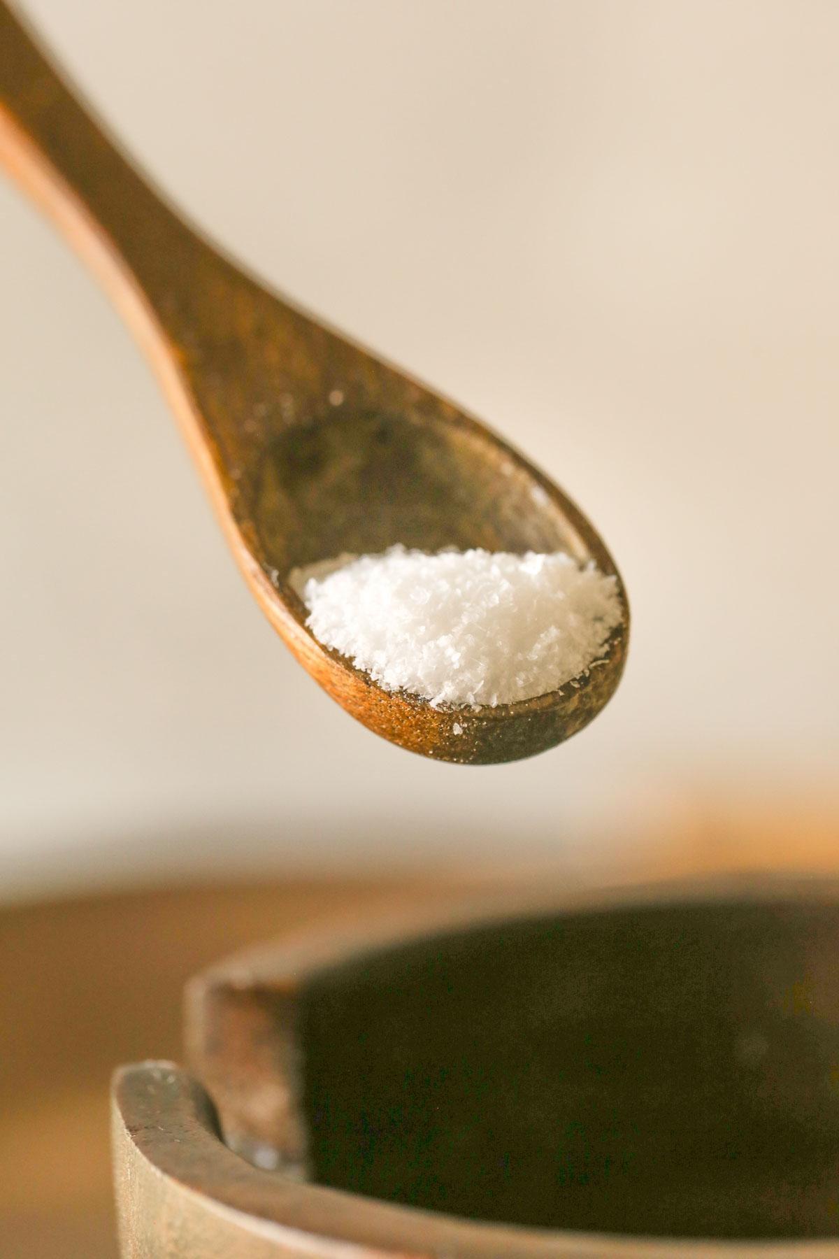 Close up shot of a wooden teaspoon of salt.  