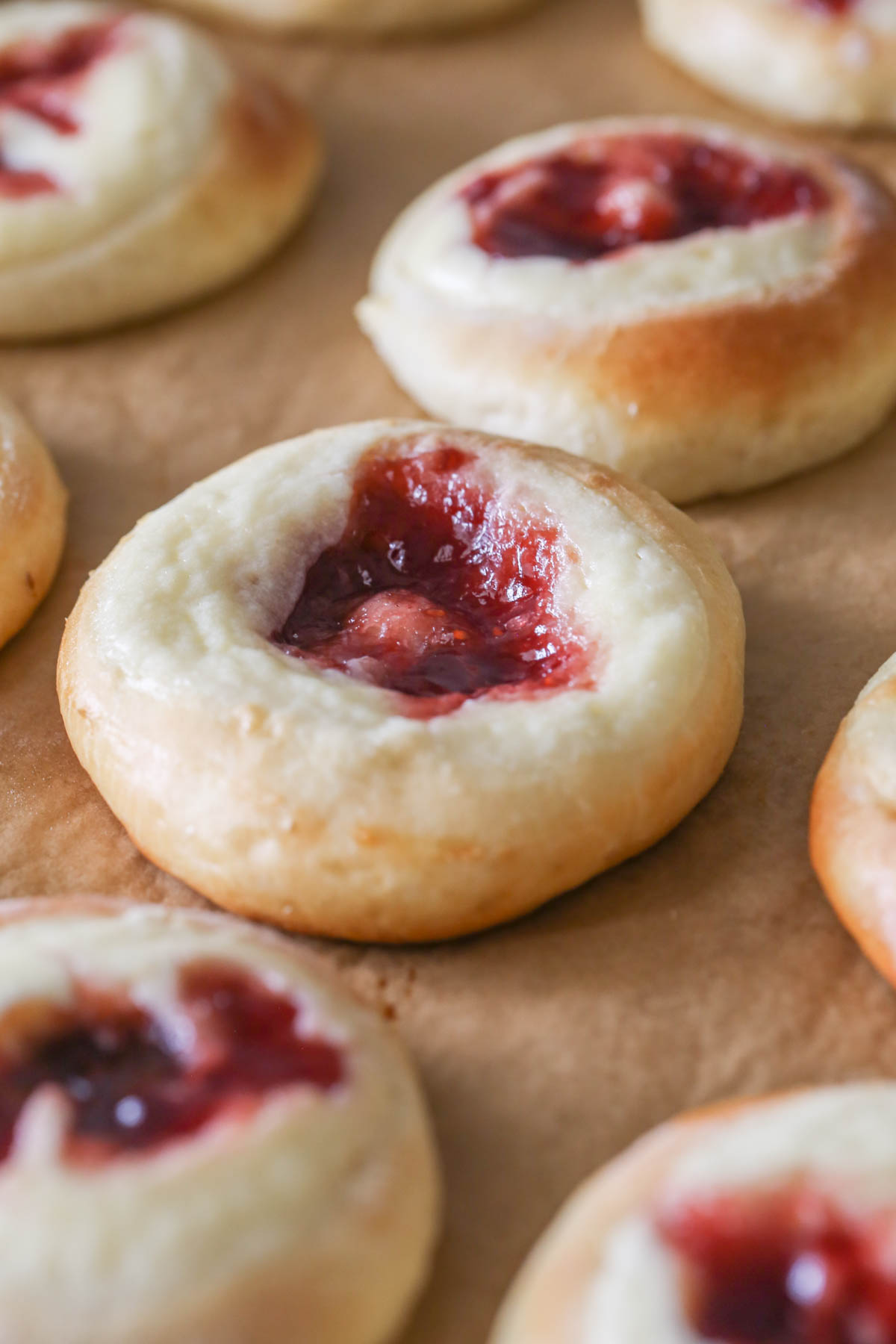 Close up shot of Raspberry Cream Cheese Kolaches on parchment paper after being baked. 