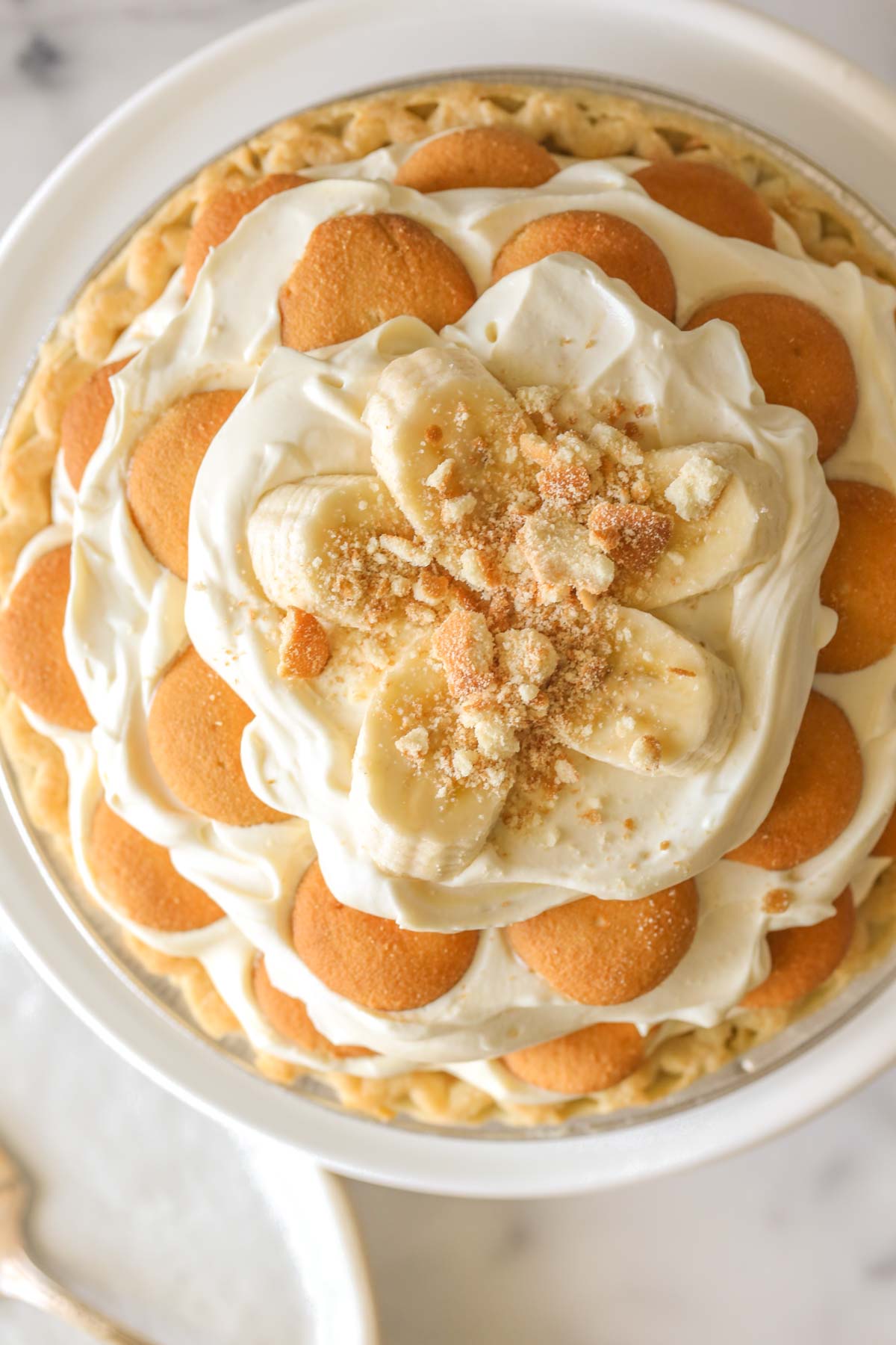 Close up, overhead shot of Mile High Banana Pudding Pie on a white cake stand.  