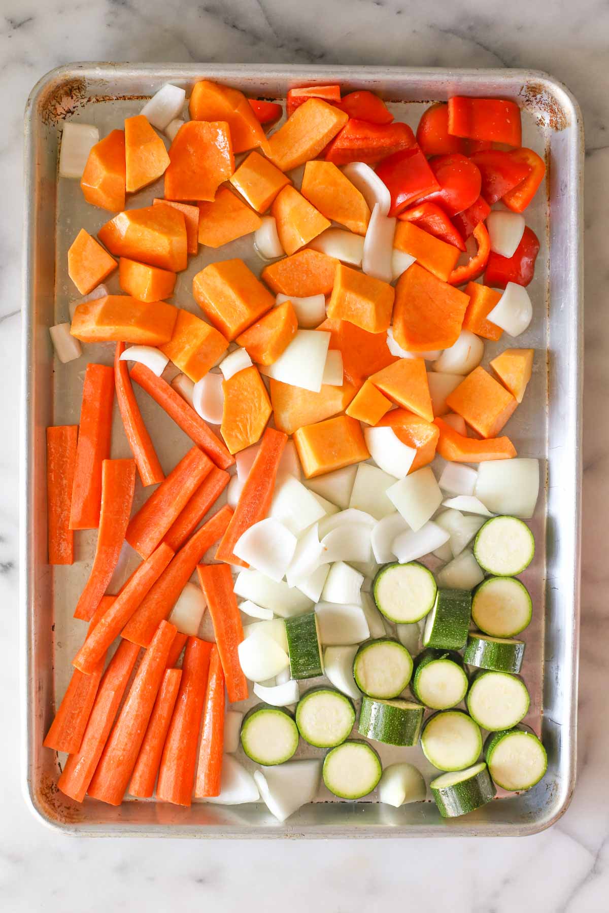 Overhead shot of the prepared squash, carrots, zucchini, pepper and onion on a baking sheet before being roasted for the Roasted Vegetable Soup.  