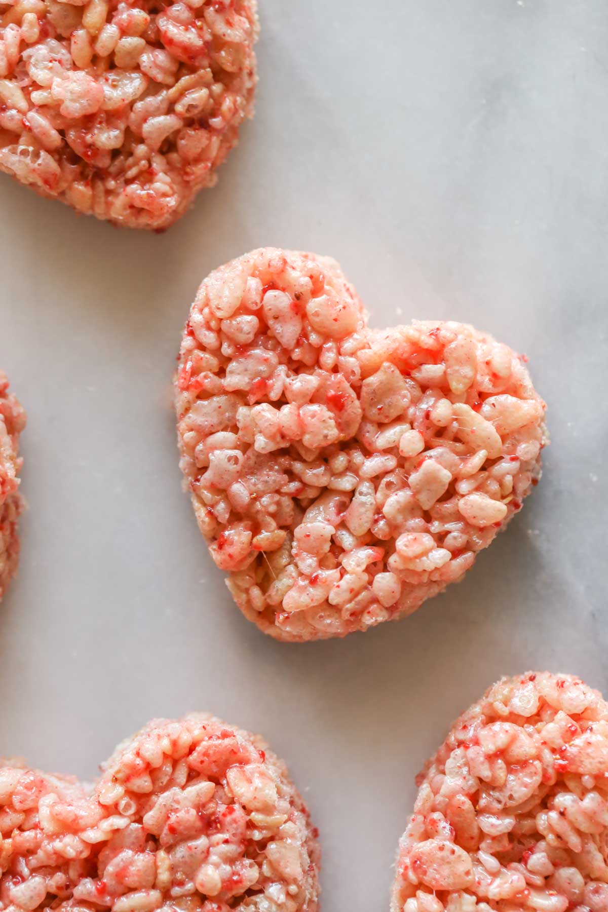 Close up shot of heart shaped Strawberry Rice Krispie Treats on a marble background. 