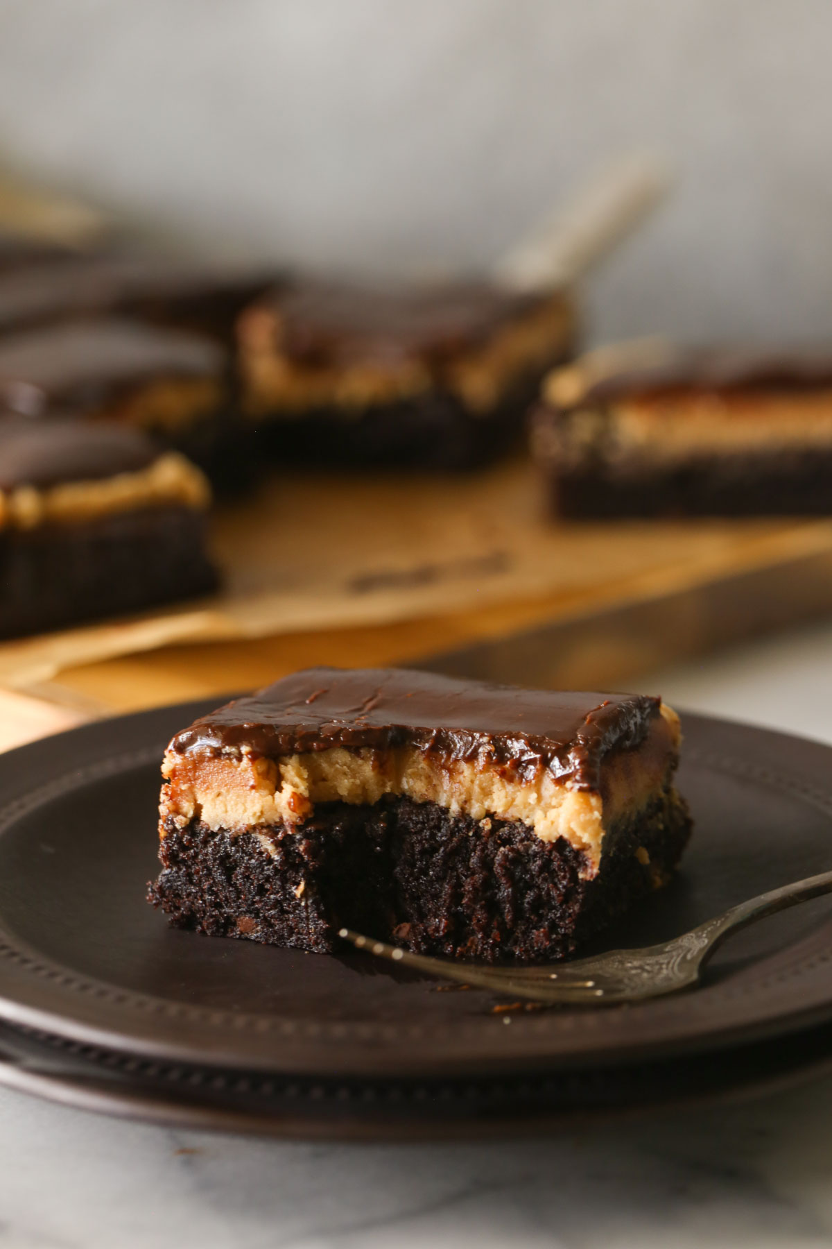 A Chocolate Peanut Butter Brownie on a plate with a fork, with more brownies in the background. 