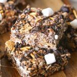 Close up shot of two S'more Bars stacked on a wood cutting board with more bars in the background.