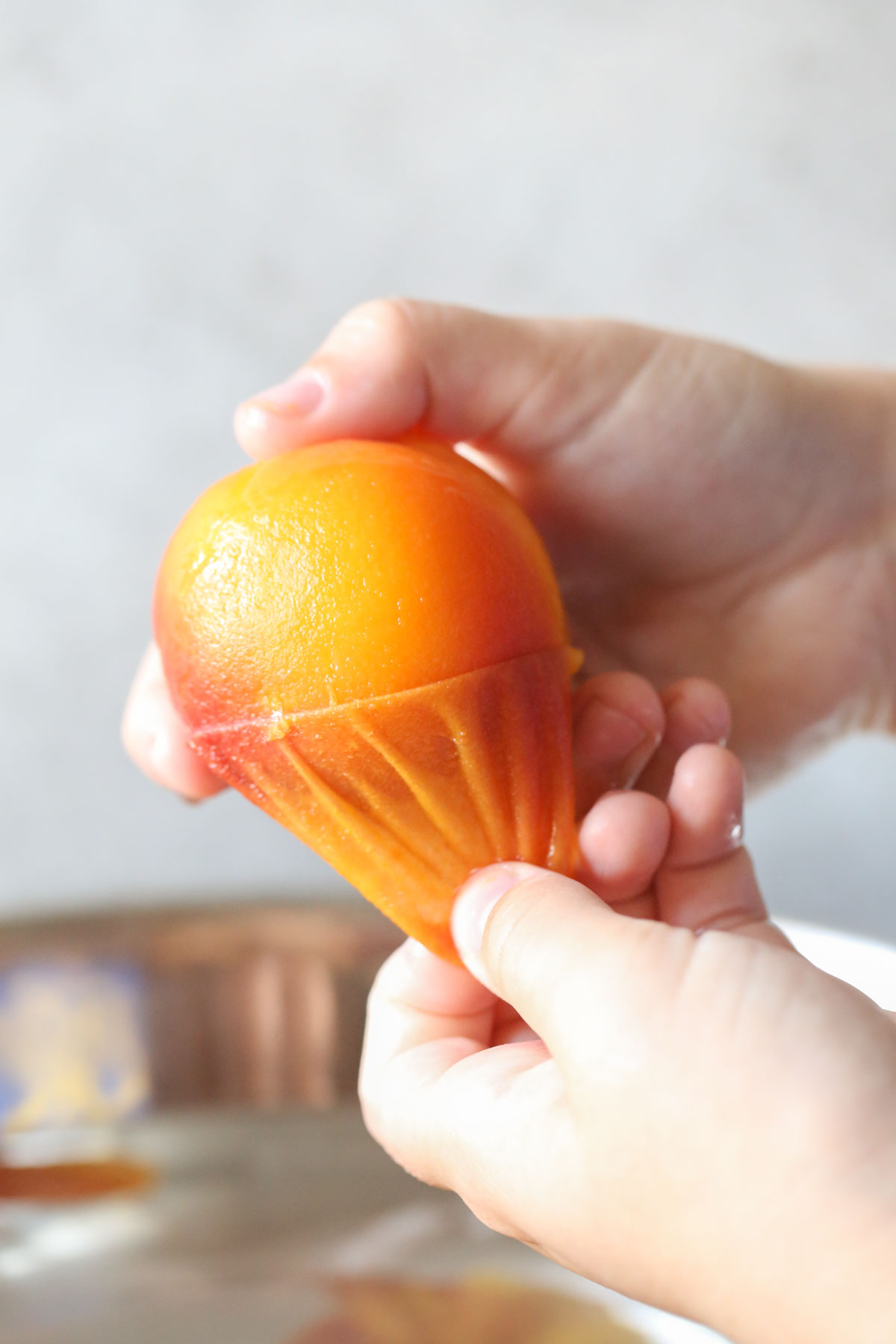 Close up shot of a hand pulling off the peeling from the peach.  