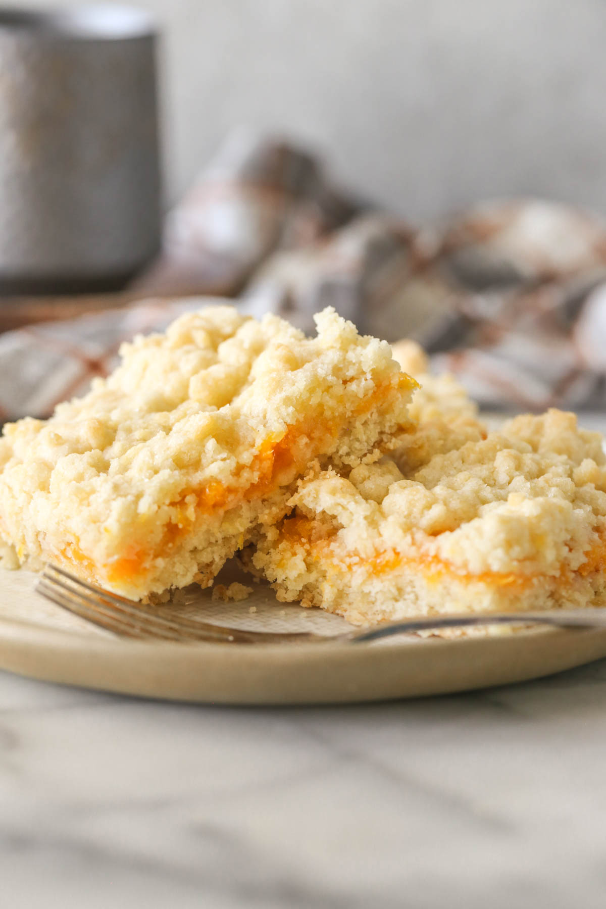 Three Peach Crumb Bar squares on a plate with a fork.  