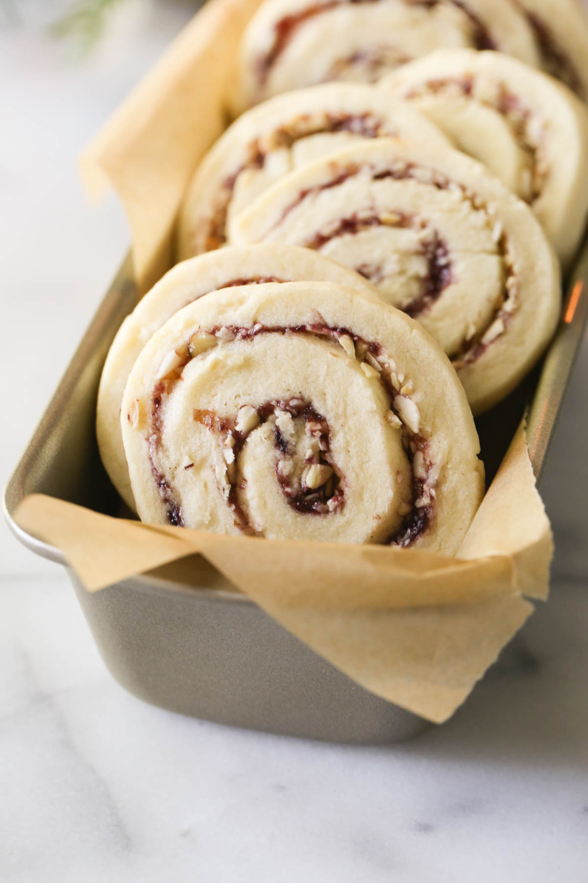 Close up shot of Raspberry Almond Pinwheels arranged in a parchment paper lined mini loaf pan.  