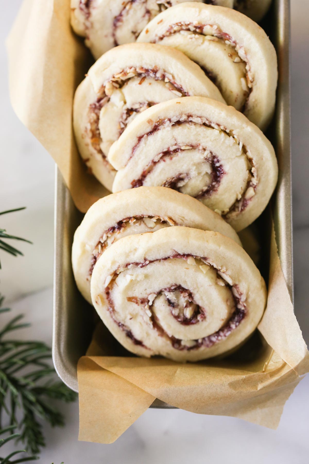 Overhead close up shot of Raspberry Almond Pinwheels arranged in a parchment paper lined mini loaf pan.  