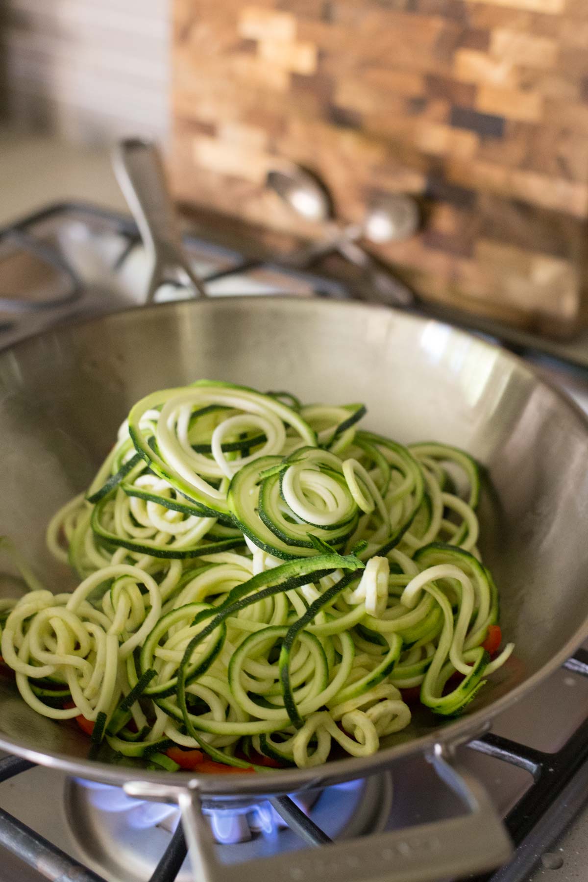 A large wok with red pepper strips and spiralized zucchini in it for the Spicy Korean Beef and Zoodles.  